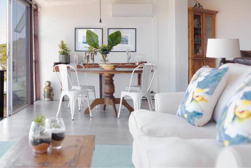 a living room with a white couch and a table at Rocky Bay on the View in Gordonʼs Bay