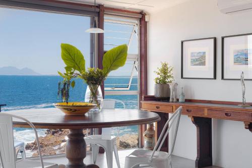 a dining room with a table and a view of the ocean at Rocky Bay on the View in Gordonʼs Bay