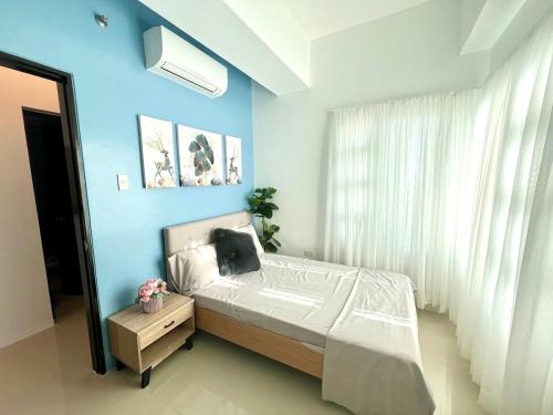 a bedroom with a bed and a blue wall at jovi's Condo one pavilion place in Cebu City
