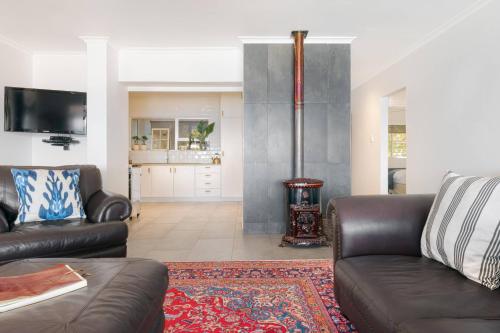 a living room with two leather couches and a fireplace at Rocky Bay on the View in Gordonʼs Bay
