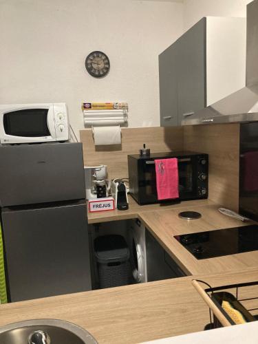une petite cuisine avec un micro-ondes et un réfrigérateur dans l'établissement Appartement dans villa à 600m de la plage, à Fréjus