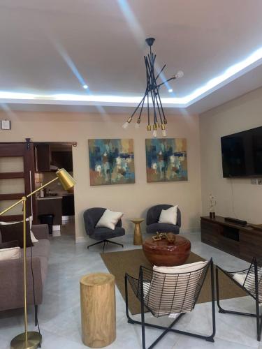 a living room with a couch and chairs and a tv at Cozy 2-Bedroom Apartment in Accra in Ofako