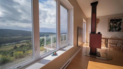 a room with large windows with a table and a view at Eagles Perch in Margaree