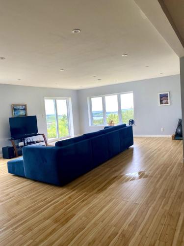 a living room with a blue couch and wooden floors at Eagles Perch in Margaree