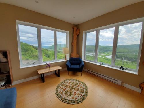 a living room with large windows and a blue chair at Eagles Perch in Margaree
