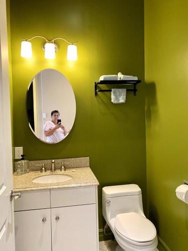 a man taking a picture of a bathroom with a mirror at Eagles Perch in Margaree