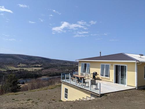 a yellow house with a deck with chairs on it at Eagles Perch in Margaree