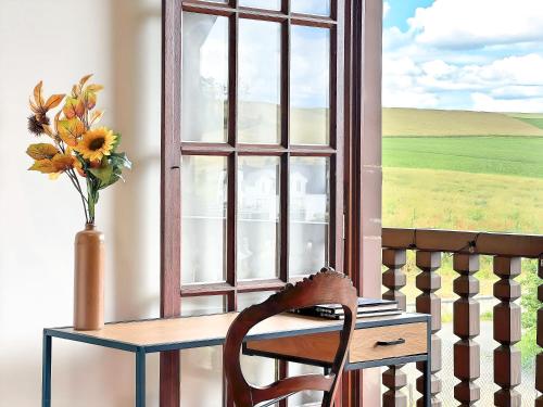 a chair sitting in front of a window with a vase of flowers at Spacious 150 sqm Home in a Natural Setting with Easy Access & Private Courtyard Parking - Balcony, Fire Pit, Ping-Pong, and Relaxing Outdoor Amenities in Gingsheim