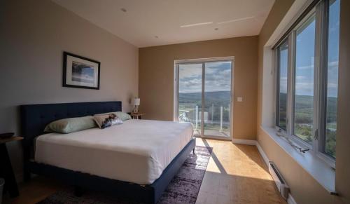 a bedroom with a large bed and large windows at Eagles Perch in Margaree