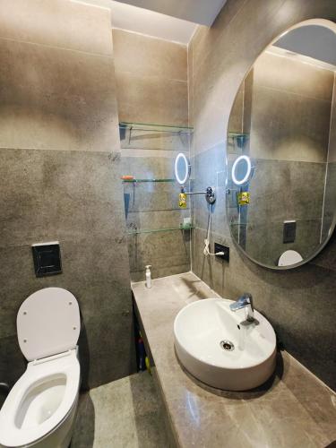 a bathroom with a toilet and a sink and a mirror at Luxurious Suite with Panoramic glass wall in Ghaziabad