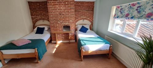 two twin beds in a room with a brick wall at Earsham Street House in Bungay