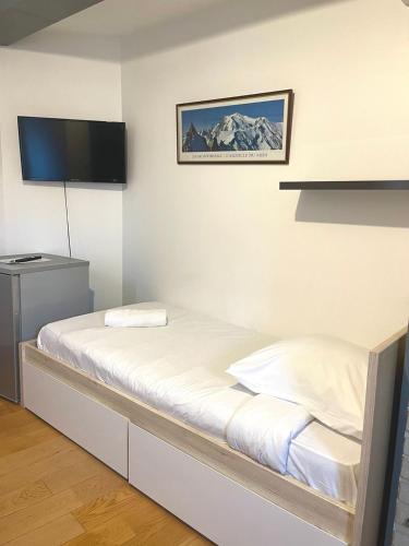a bedroom with a bed with a tv on the wall at Les Chambres d'Orsay in Orsay