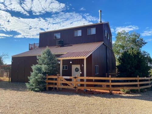 a barn with a wooden fence in front of it at Kanab Barn Loft House on 40 acres Pet Friendly in Kanab