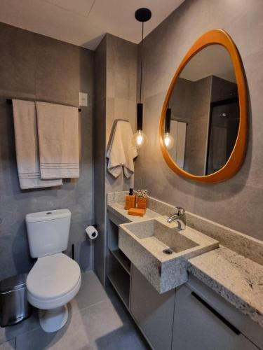 a bathroom with a toilet and a sink and a mirror at Yoo 914 - Luxury Loft in Porto Alegre