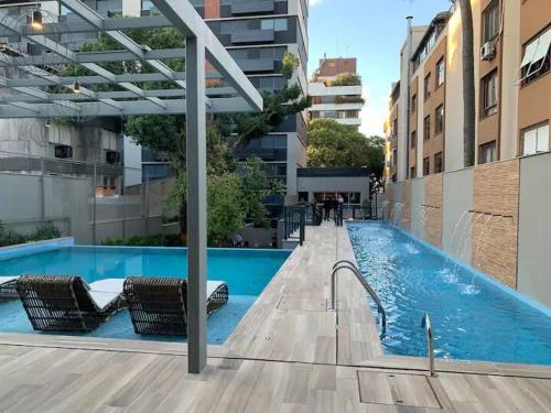 una piscina con sedie accanto a un edificio di Yoo 914 - Luxury Loft a Porto Alegre