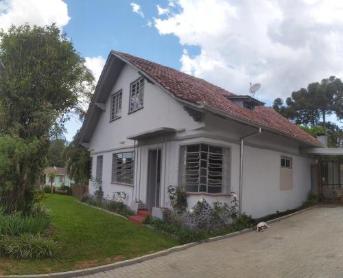 a white house with a dog sitting in the driveway at Hospedaria 71 in Campo Alegre
