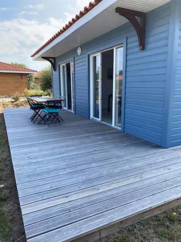 une maison bleue dotée d'une terrasse en bois avec une table dans l'établissement Charmante villa, à Parentis-en-Born