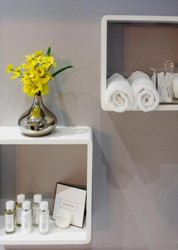 a shelf with towels and a vase with yellow flowers at Tyndale B&B Torquay in Torquay