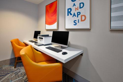 an office with a desk with a computer and two orange chairs at Holiday Inn Express Hotel & Suites Grand Rapids-North by IHG in Grand Rapids
