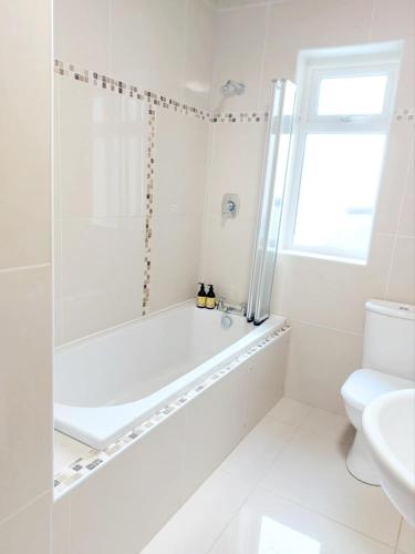 a white bathroom with a tub and a toilet at Kings in Ballyconneely