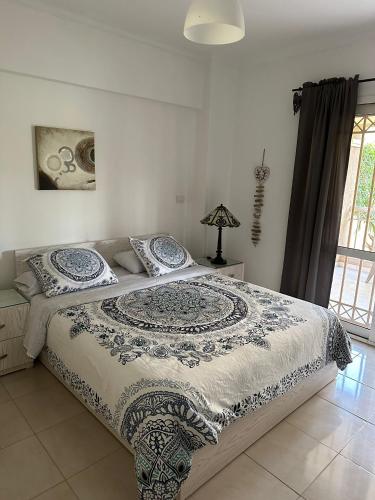 a bedroom with a bed with a blue and white blanket at Madinaty Gardens in Madinaty