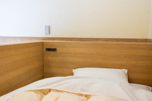 a bed in a bedroom with a wooden headboard at Sengokuhara Shinanoki Ichinoyu in Hakone
