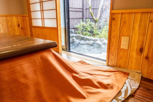 a bed in a room next to a window at Sengokuhara Shinanoki Ichinoyu in Hakone