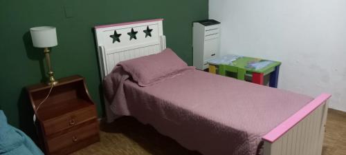 1 dormitorio con cama rosa y pared verde en Departamento Familiar con estacionamiento incluido, en Bahía Blanca