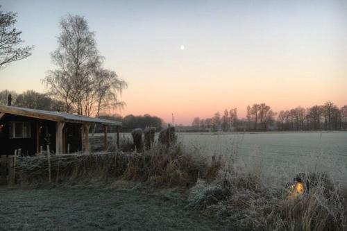 a house in a field next to a field of grass at Chalet Op de Brusse in De Heurne