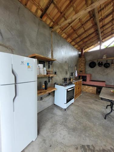 a kitchen with a white refrigerator and a table at Nosso Quintal Candeias - Camping in Conceição do Mato Dentro