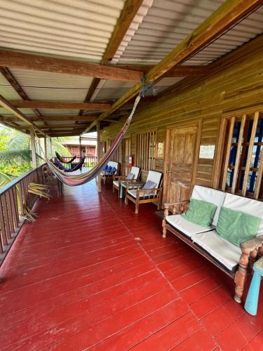 a porch with couches and a hammock on it at Valerie Emanuel Apartments in Bocas del Toro