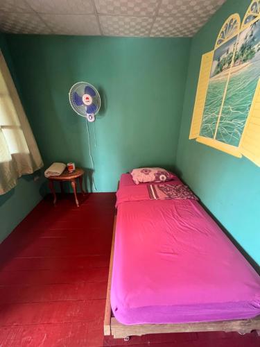 a small bedroom with a pink bed and a fan at Valerie Emanuel Apartments in Bocas del Toro