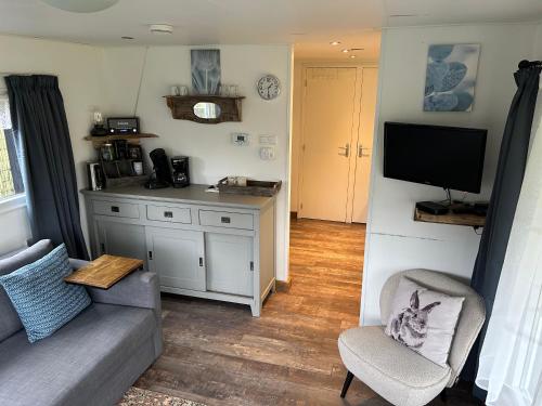 a living room with a couch and a tv at Chalet Op de Brusse in De Heurne