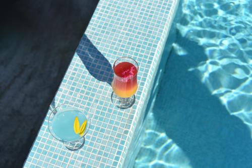 a drink in a glass next to a swimming pool at Banja na Drini - Lux vikendice, apartmani, na obali reke in Banja Koviljača