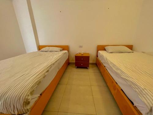 two beds in a room with a nightstand between them at Nile Panorama Hotel in Luxor