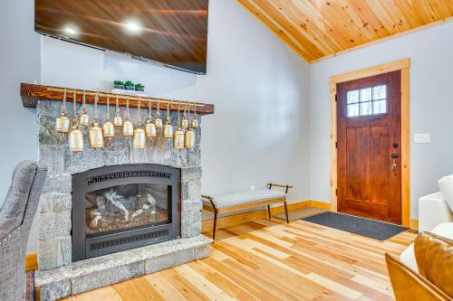 a living room with a stone fireplace with a chandelier at 6 Mi to Lake Winnipesaukee New Hampshire Home in Gilford