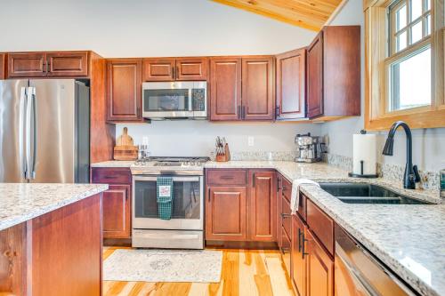 a kitchen with wooden cabinets and stainless steel appliances at 6 Mi to Lake Winnipesaukee New Hampshire Home in Gilford