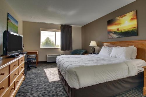 a hotel room with a bed and a flat screen tv at EverSpring Inn & Suites in Oskaloosa