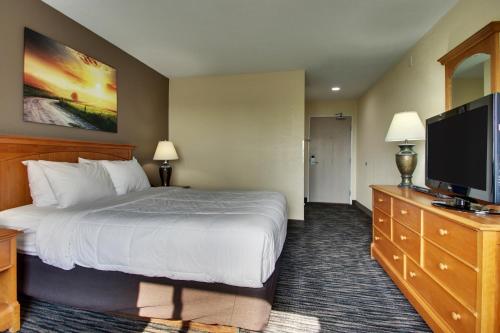 a hotel room with a bed and a flat screen tv at EverSpring Inn & Suites in Oskaloosa
