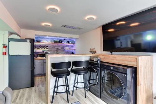 a kitchen with a bar with stools and a tv at Modern Chic Retreat Luxe Comfort and Style in Omaha