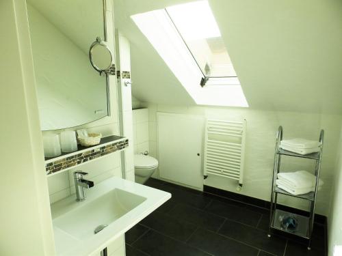 a white bathroom with a sink and a skylight at H41 Inn Hotel Garni Freiburg in Freiburg im Breisgau