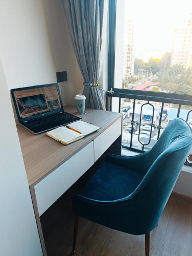 a desk with a laptop and a chair next to a window at Eika - Refined and luxurious studio Apartment in Nairobi
