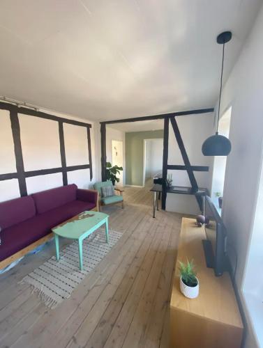 a living room with a purple couch and a table at Cozy and Central in Helsingør