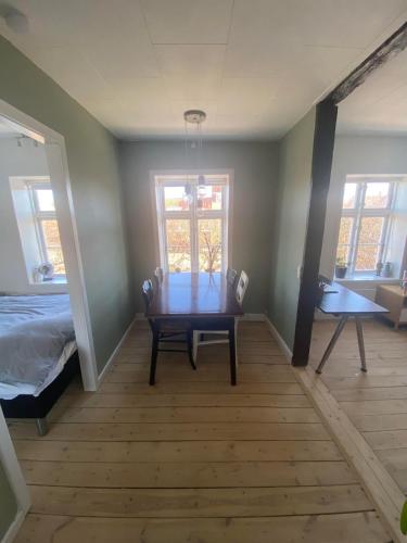 a room with a table and a bed and windows at Cozy and Central in Helsingør