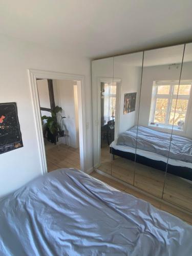 a bedroom with a mirror and a bed in it at Cozy and Central in Helsingør