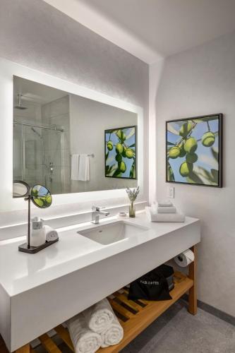 a white bathroom with a sink and a mirror at Olivia Hotel in Los Angeles