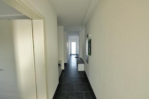 a hallway with white walls and a black tile floor at Panoramatraum in Gersdorf
