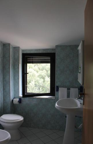 a bathroom with a toilet and a sink and a window at Casa Kalavrìa a 50mt dal mare in Nicotera Marina