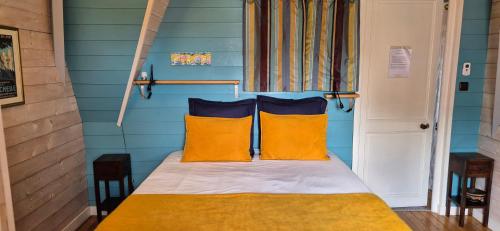 Un dormitorio con una cama con dos almohadas amarillas. en Chambres d'hôtes Le Clos Bleu, en La Rochelle