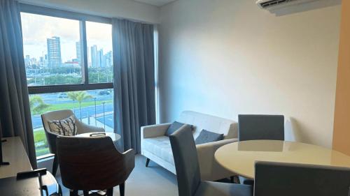 a living room with a couch and a table and a window at Parque do Cais - Flats Premium no Recife por Yolo in Recife